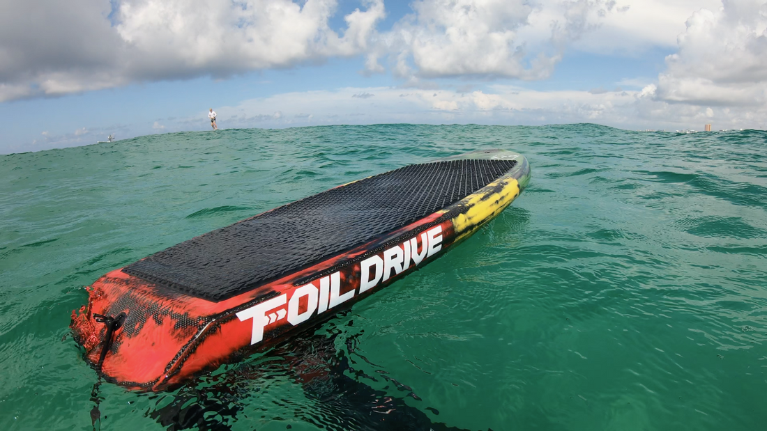 Red and black Foil Drive board on a body of water with a cloudy sky.